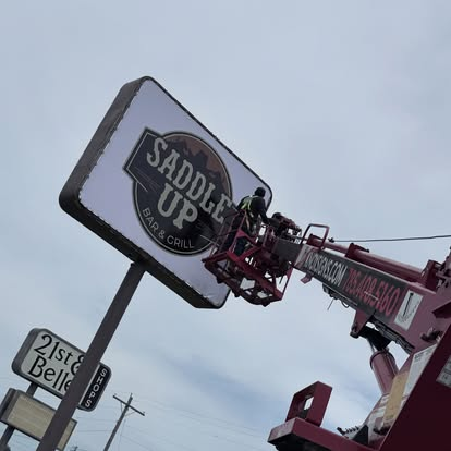 Saddle Up sign being installed at 21st & Belle